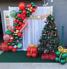 christmas decorations and balloons are on display in front of a building with a sign that says merry