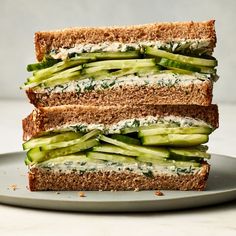 two sandwiches stacked on top of each other with cucumbers and cheese in between them