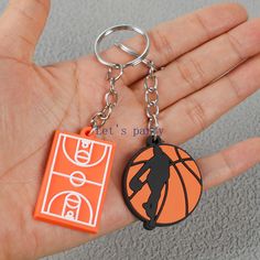 a hand holding an orange and black basketball keychain with a person on it