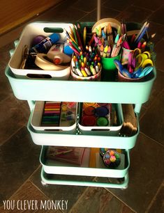 a cart filled with lots of art supplies on top of a floor next to a tile floor