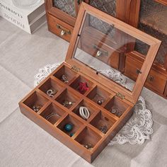 an open wooden jewelry box sitting on top of a white doily next to drawers