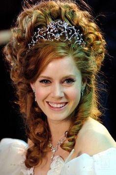 a woman wearing a tiara and smiling at the camera with her hair pulled back