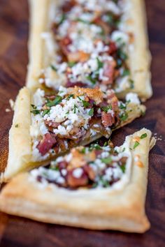 two flatbreads with meat and cheese on them sitting on a table next to each other