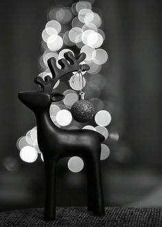 a black and white photo of a reindeer ornament with lights in the background