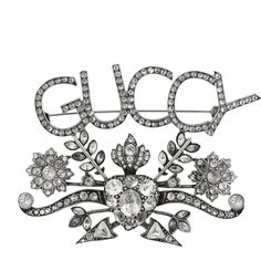 The Gucci GUCCY Crystal Brooch in Silver is a sparkling, silver-tone brooch crafted in Italy. This accessory features a crystal encrusted "GUCCY" logo on top of a swirling flower design. The back is patterned with delicate line work and has the classic pin closure. 100% Silver-tone metal BroochPin "GUCCY" logo Flower detailing Crystal encrusted Line work and Gucci logo on back Pin style closure 3.5" x 2.5" Made in Italy Logo Flower, Gucci Logo, Line Work, White Crystals, Crystal Brooch, Heart With Arrow, Flower Design, The Fashion, Flower Designs