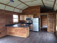 an empty kitchen with wood paneling on the walls and floor is seen in this image