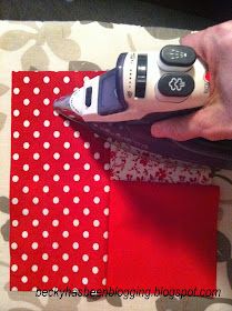 a person is holding a remote control in their left hand, on top of a piece of fabric