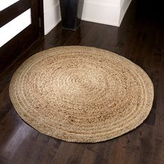 a large round rug is on the floor in front of a door with a vase next to it