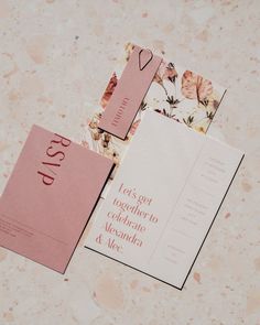 two wedding stationery cards on a marble surface