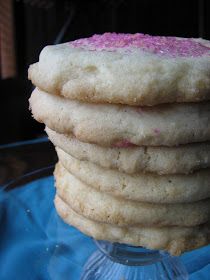 a stack of cookies with pink sprinkles sitting on top of a glass plate