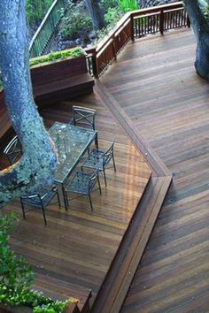 a wooden deck with table and chairs next to trees