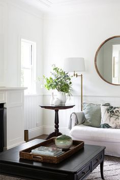 a living room with a couch, coffee table and mirror on the wall above it