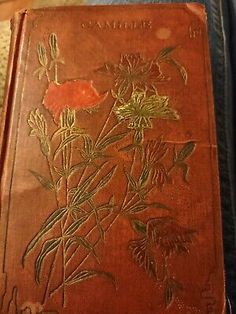 an old leather book with flowers on the front and back cover, sitting on a couch