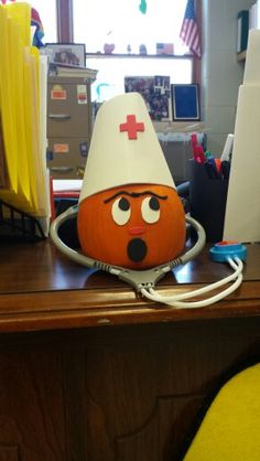 an orange with a medical hat on it's head is sitting on a desk