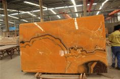 a man standing next to a large orange marble slab in a warehouse filled with tables and chairs