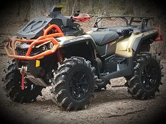 an orange and black four - wheeler parked in the dirt with mud tires on it