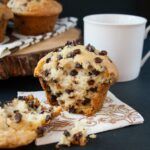 chocolate chip muffins sitting on top of a napkin next to a cup of coffee