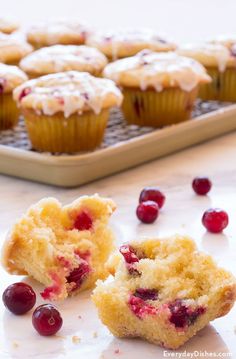 some cranberry muffins are on a cooling rack and one is broken in half