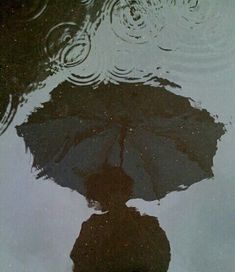 an umbrella reflecting in the water on a rainy day