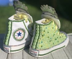 a pair of green and white shoes with pearls on them sitting on a wooden surface