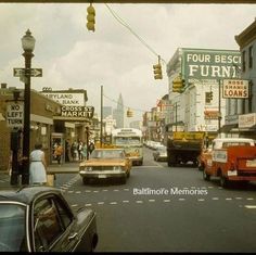 cars are driving down the street in front of stores