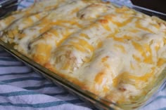 a casserole dish sitting on top of a blue and white table cloth covered in cheese