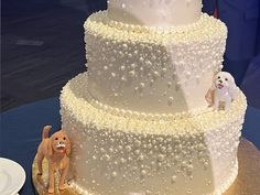 a three tiered cake with white frosting and dog figurines