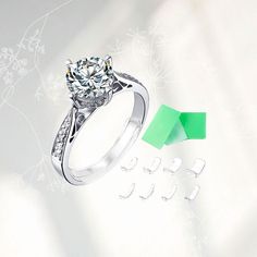 a diamond ring with three pieces of green paper in front of it