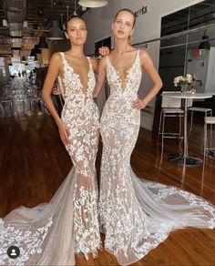 two women standing next to each other on a wooden floor wearing dresses with white flowers