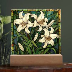 a stained glass panel with white lilies in the center and green foliage behind it