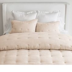 a bed with white linens and pillows on it