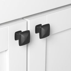 two black handles are on the white cabinet doors