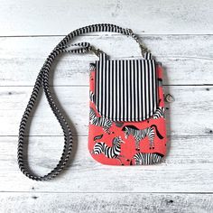 an orange and black zebra print purse on a white wooden background with a striped strap