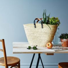 a wooden table topped with a basket filled with plants