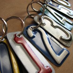 several different colored metal key chains on a table with one being held by a pair of scissors