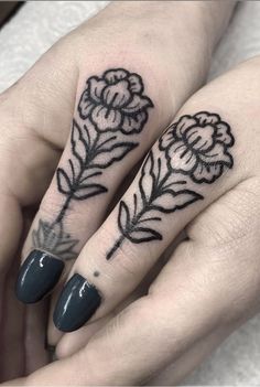 two hands with tattoos on them and one has a flower tattooed on the middle finger