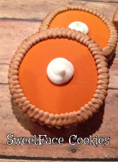 two cookies with white frosting are on a wooden table