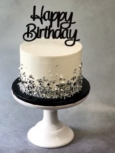 a white and black birthday cake sitting on top of a table