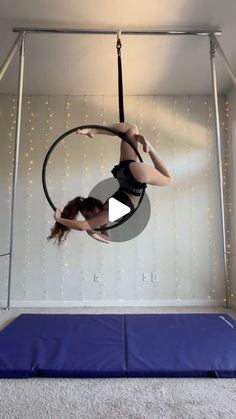 a woman is doing aerial acrobatics on a hoop in a room with lights