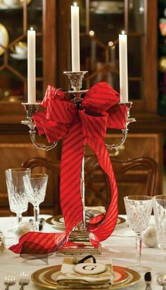 a candle holder with two candles on top of it and red ribbon around the base