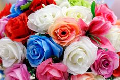 a bouquet of multicolored roses sitting on top of a blue tablecloth with white and pink flowers