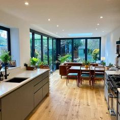 an open kitchen and living room with large windows in the backround, next to a dining table