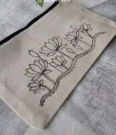 an embroidered bag with flowers on it sitting on a tablecloth covered bedding sheet