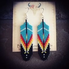 a pair of beaded earrings sitting on top of a piece of paper next to a cow skull