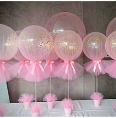 pink and gold balloons are hanging from the ceiling in front of a white tablecloth