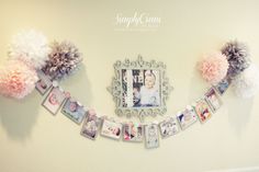 a wall with pictures and pom poms hanging on it