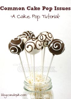 some cake pops sitting in a glass bowl with white and brown swirls on them