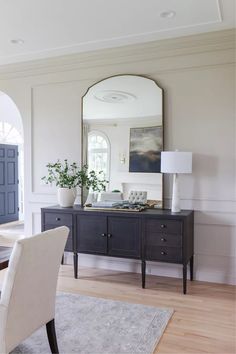 a living room with a mirror, table and chairs in it's centerpiece