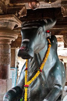 an elephant statue is adorned with flowers and beads in front of a temple building,