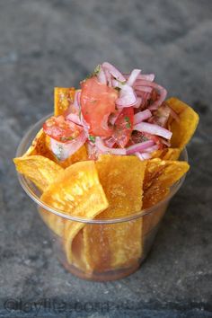 a small plastic cup filled with chips and salsa